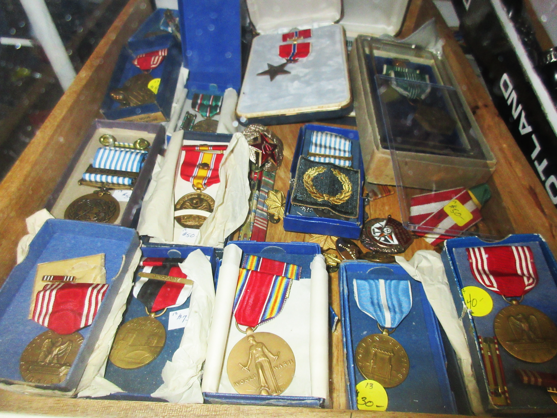 Display of military medals in open boxes, various colors and ribbons.