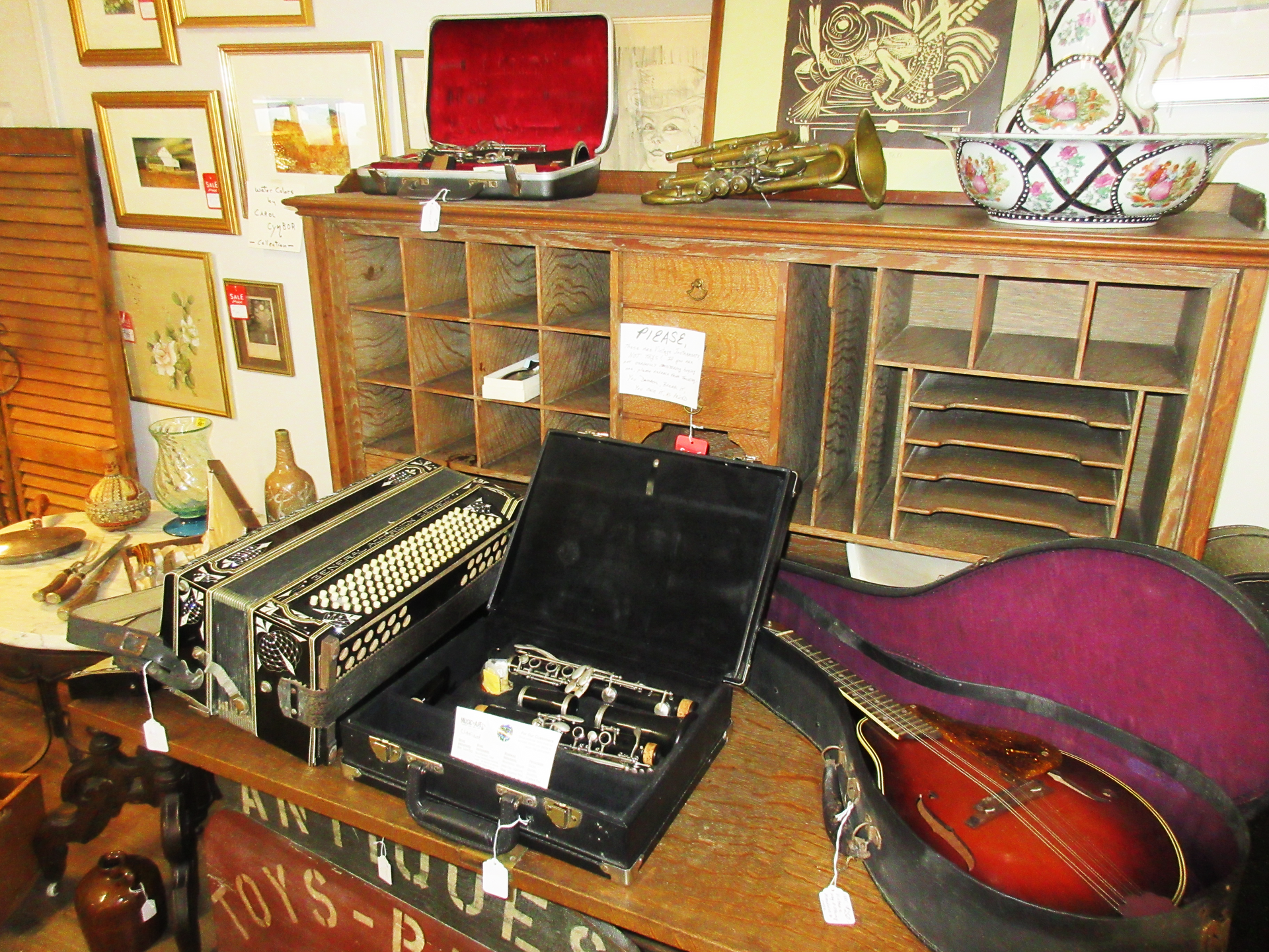 Antique shop display with musical instruments: accordion, clarinet, trumpet, mandolin, and more.