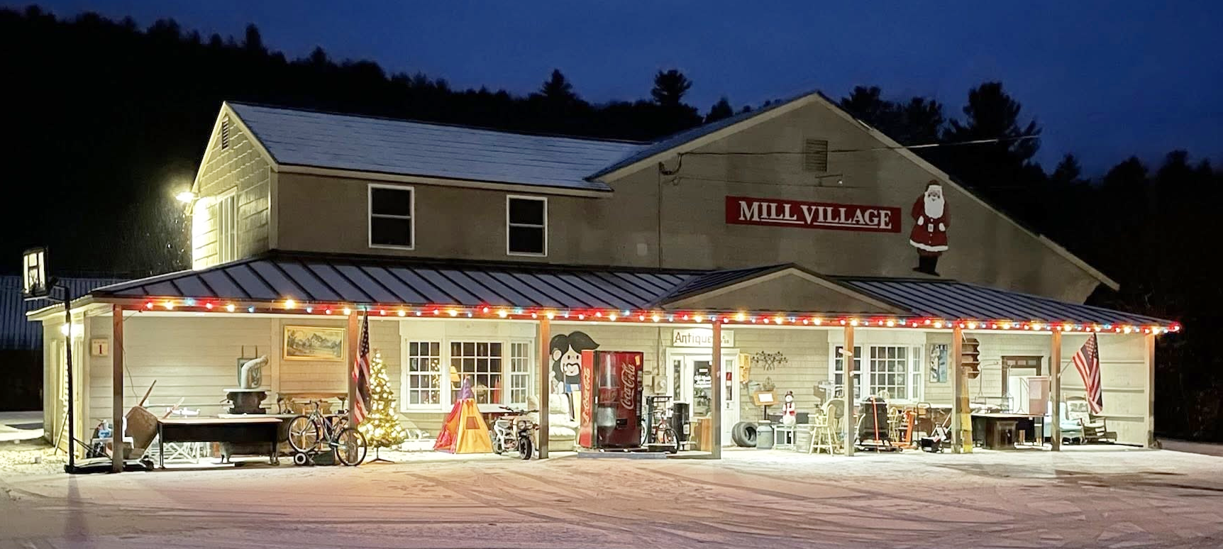 A snowy building at night decorated with Christmas lights and signs reading 