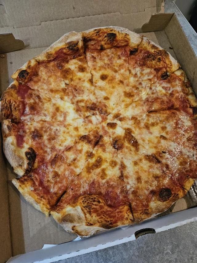Pizza in a cardboard box, with melted cheese, tomato sauce, and a golden crust.