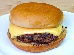 Cheeseburger on a white plate: a toasted bun, melted yellow cheese, and a grilled meat patty.