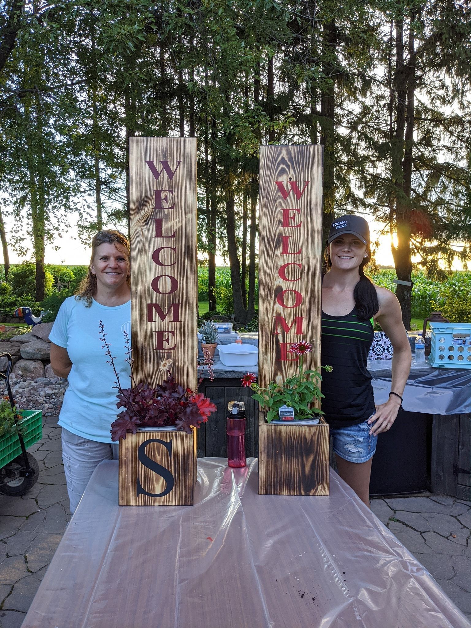 Two women are standing next to a table with wooden planters on it.
