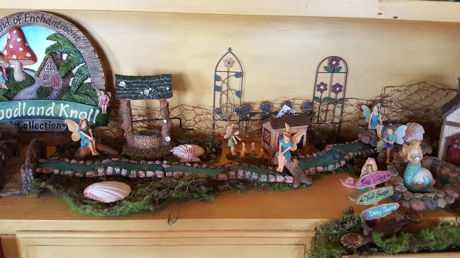 Miniature woodland scene with fairies, well, archways, and sign.