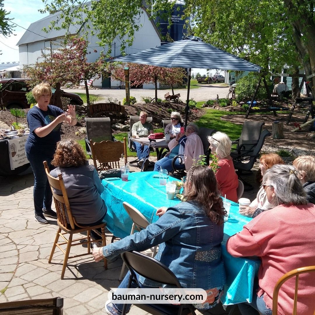 A group of people sitting around a table with the website bauman-nursery.com at the bottom