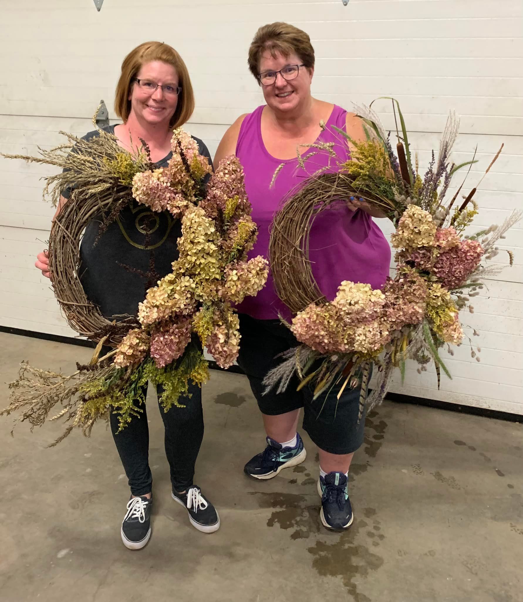 Two women are standing next to each other holding wreaths.