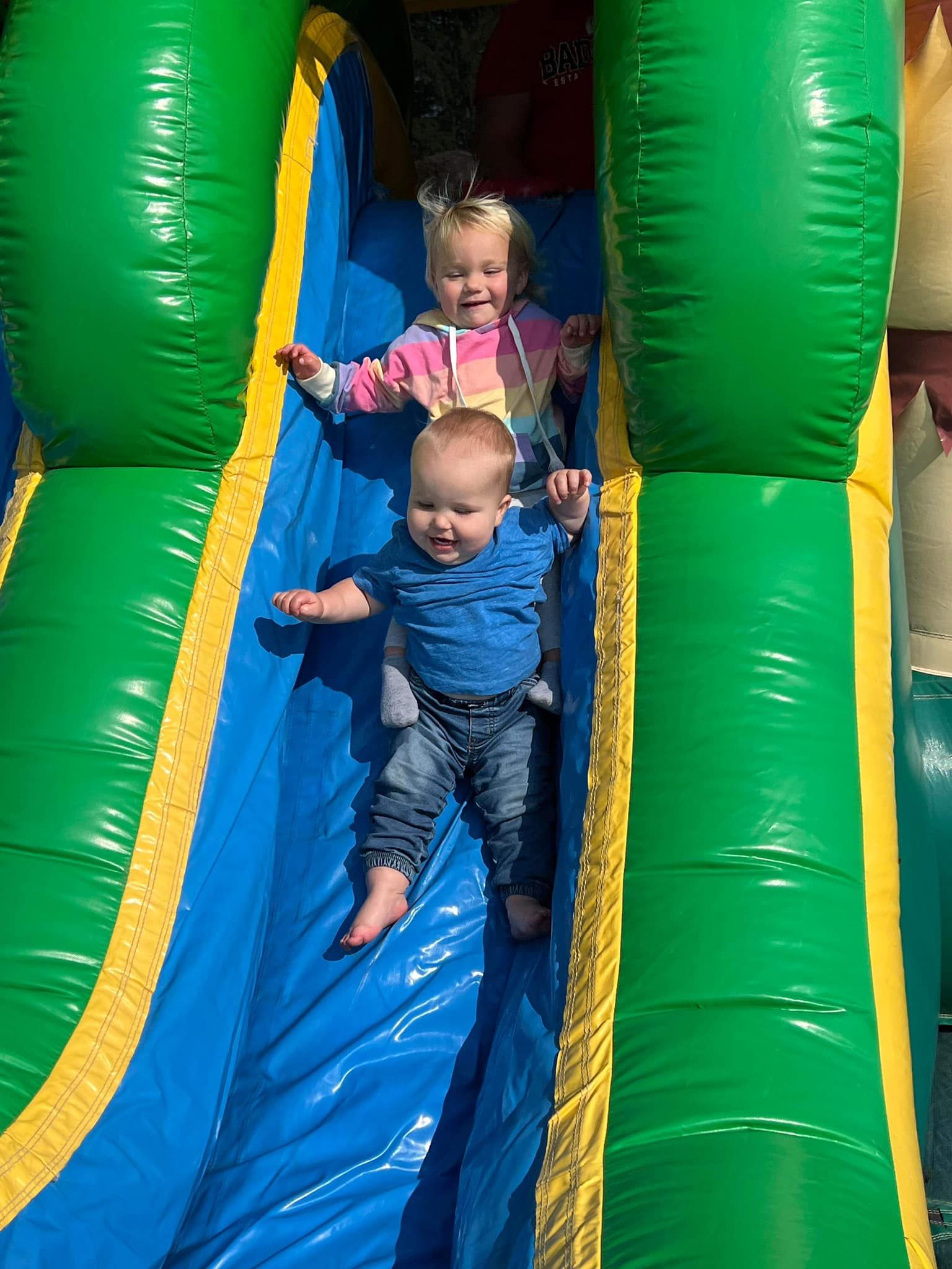 Two babies are playing on an inflatable slide.