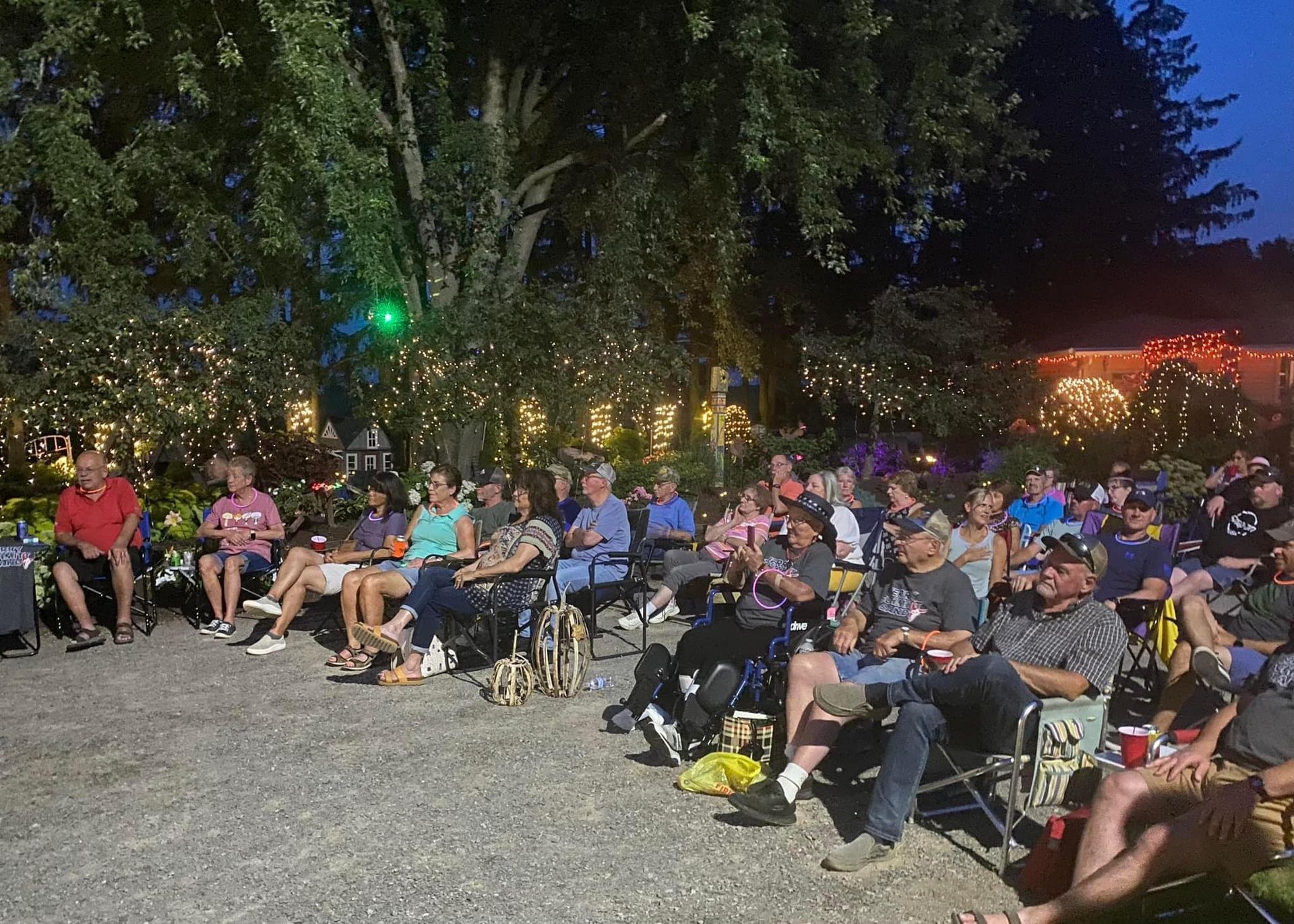 A group of people are sitting in chairs outside at night watching a movie.