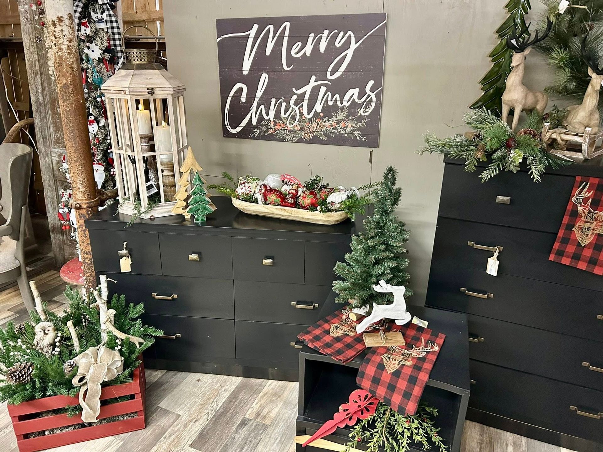 Christmas-themed display with black dressers, festive decorations, a 