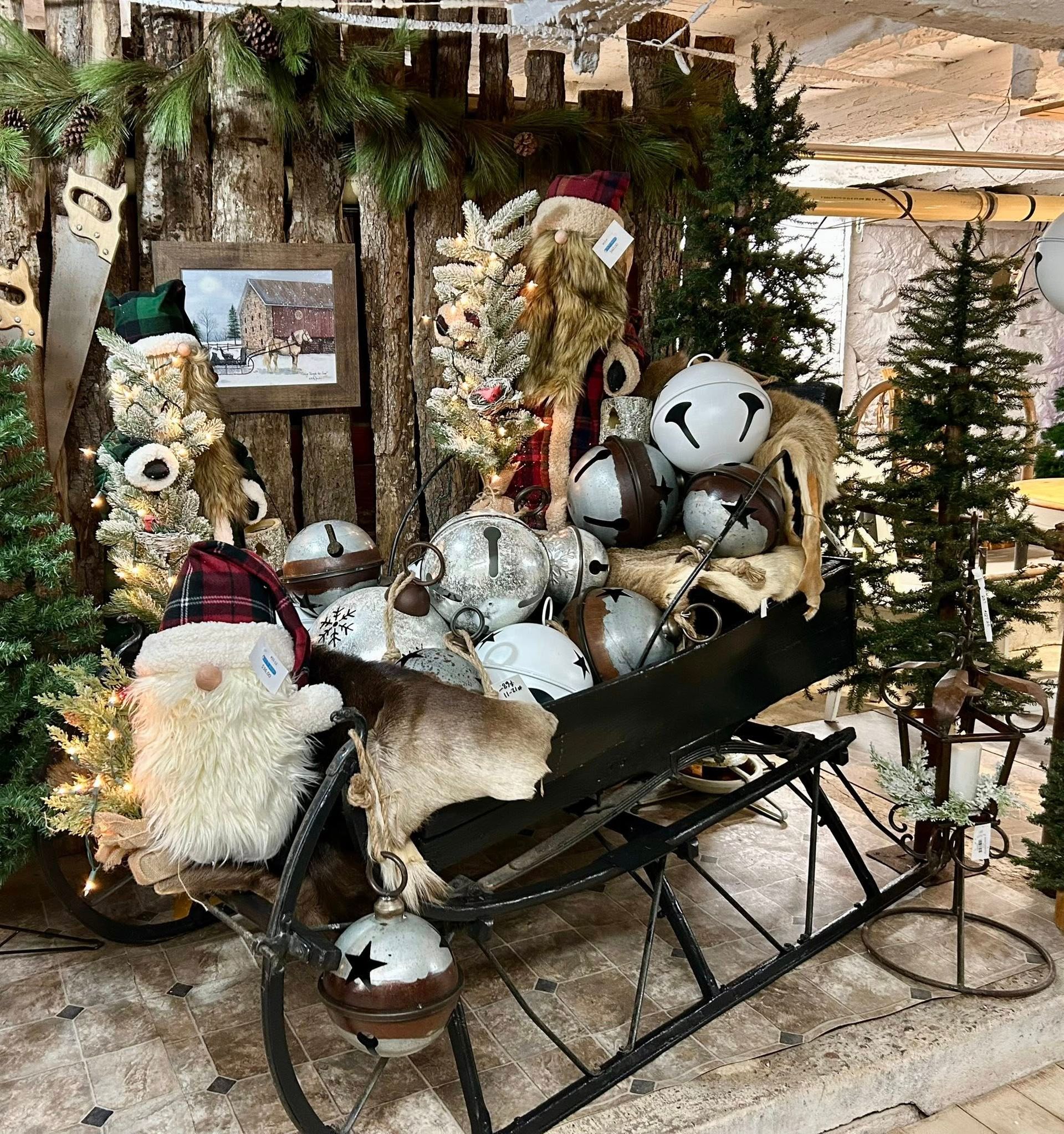 A holiday display with a sleigh, ornaments, and a plush gnome figure.