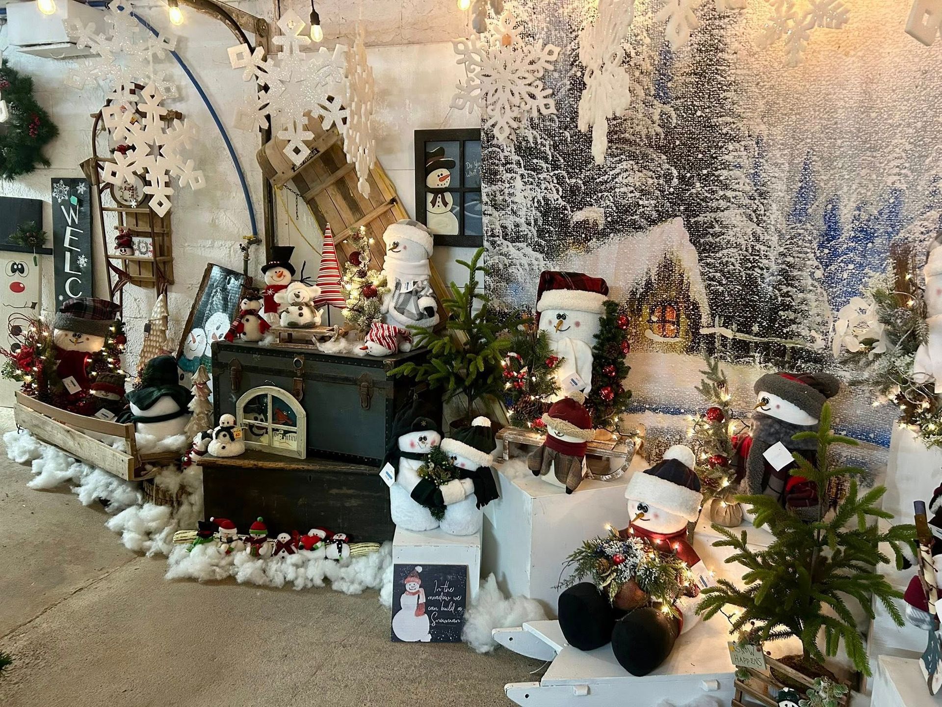 Winter-themed shop display featuring snowmen, snowy landscape backdrop, and Christmas decorations.