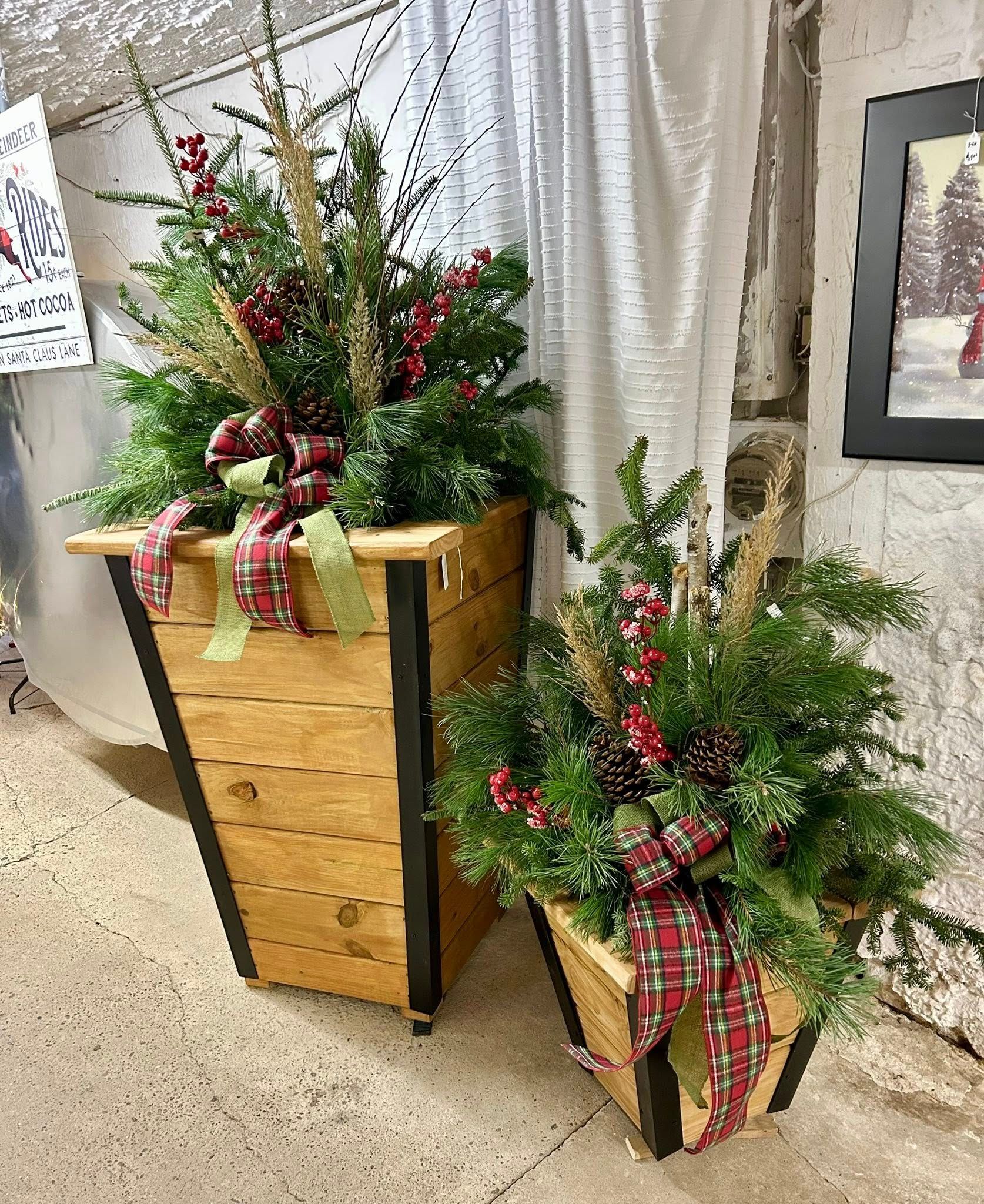 Two wooden planters with holiday greenery, red berries, and plaid ribbon.