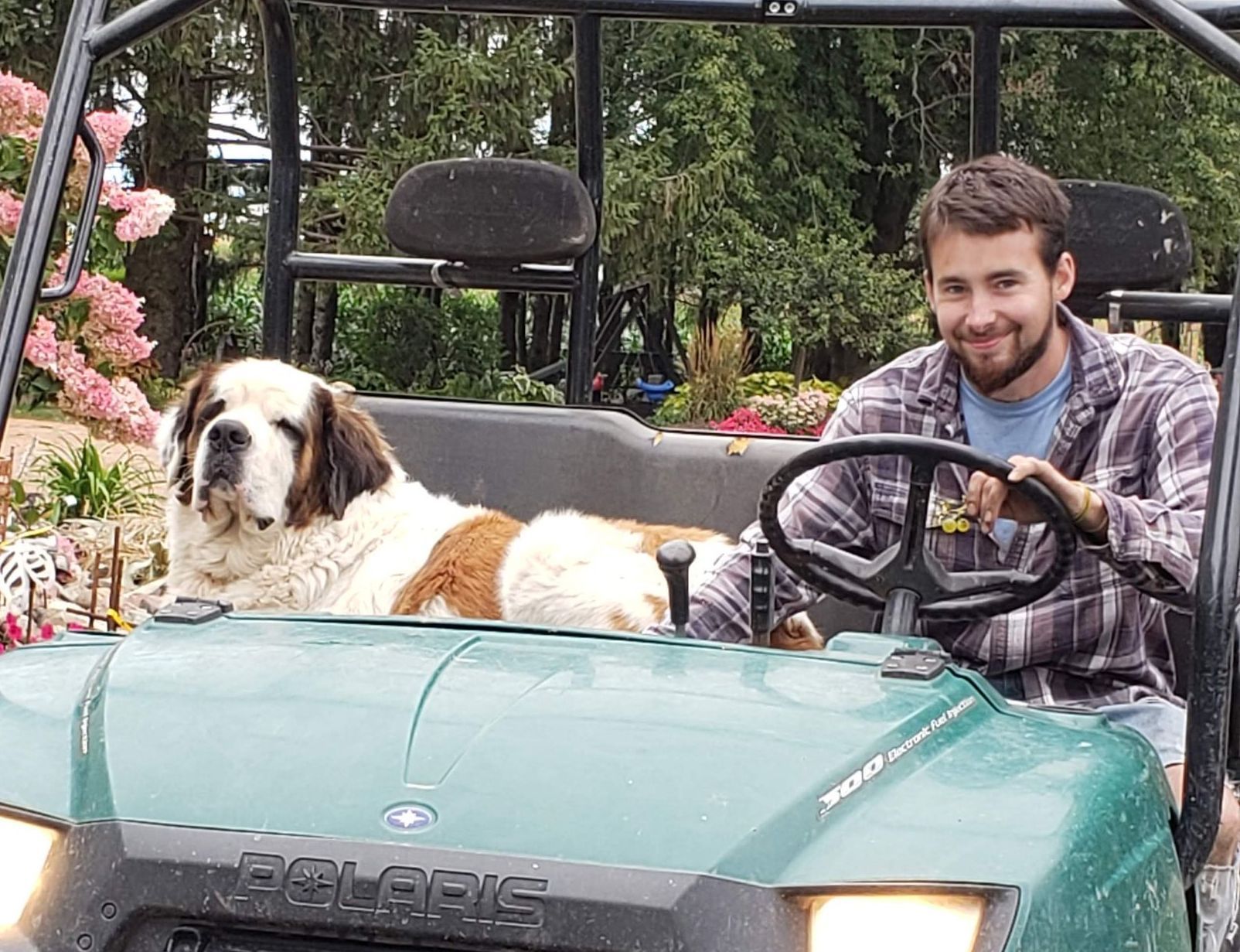 A man in a blue sweatshirt is walking out of a truck