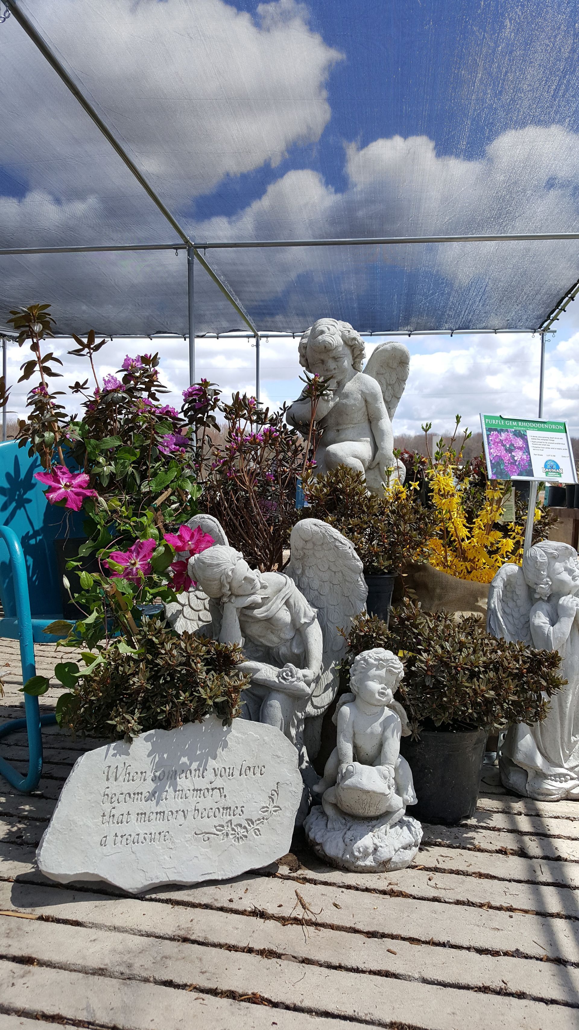 Statues of angels with flowers under a canopy with a cloudy sky.