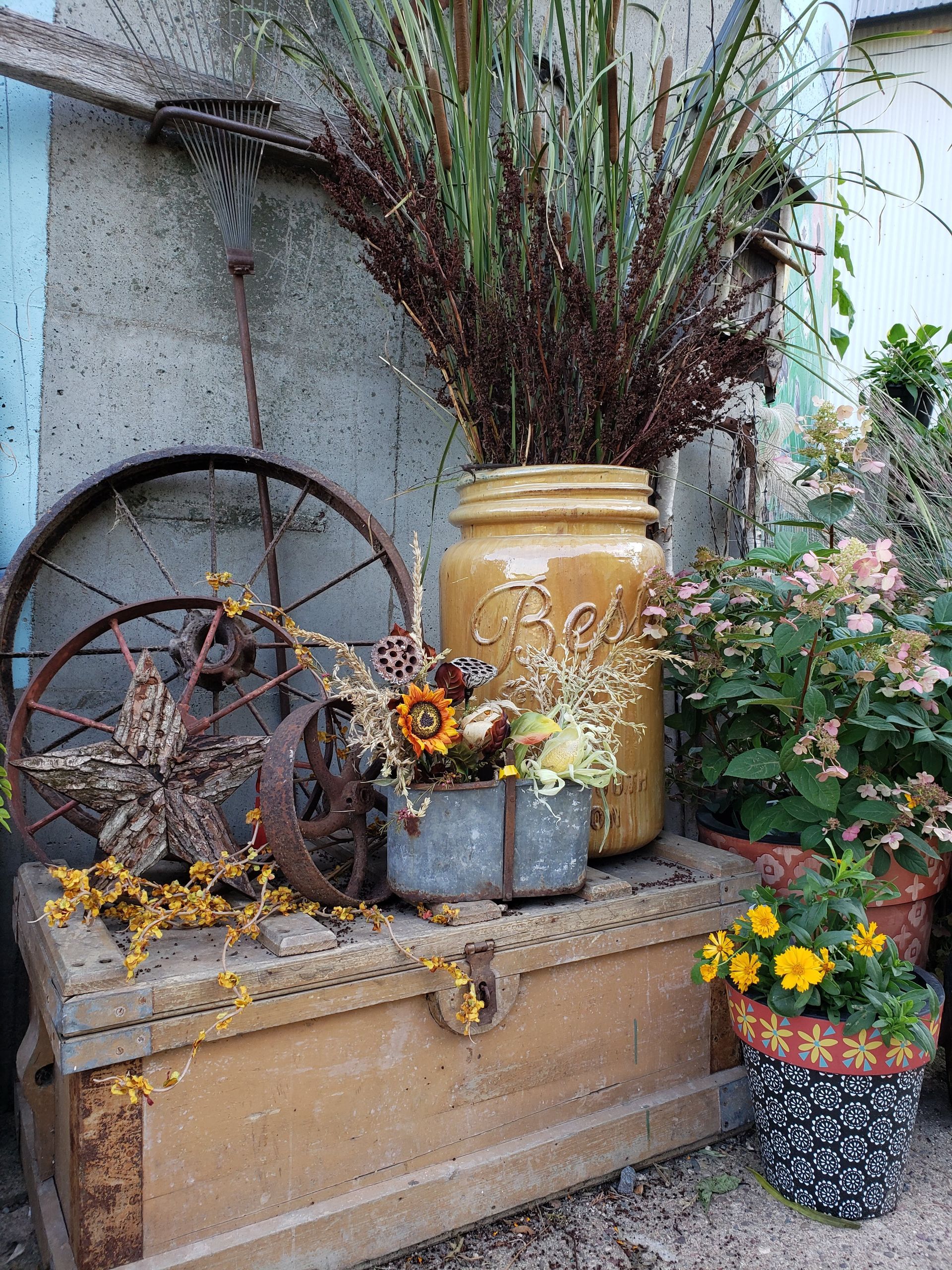 Rustic outdoor display with antique wagon wheel, jars, and flowers.