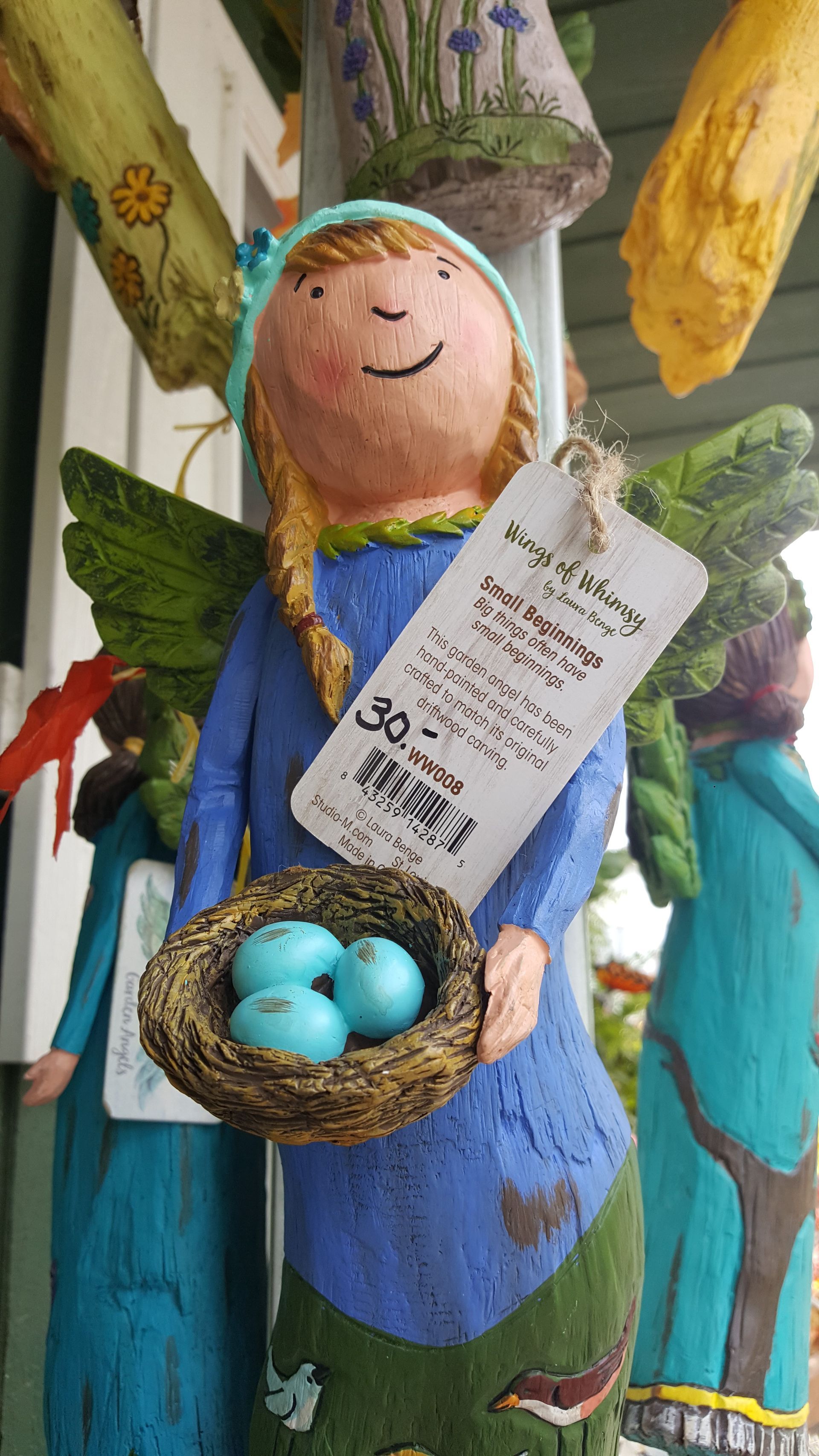 Angel statue holding a nest with three blue eggs. Price tag attached.
