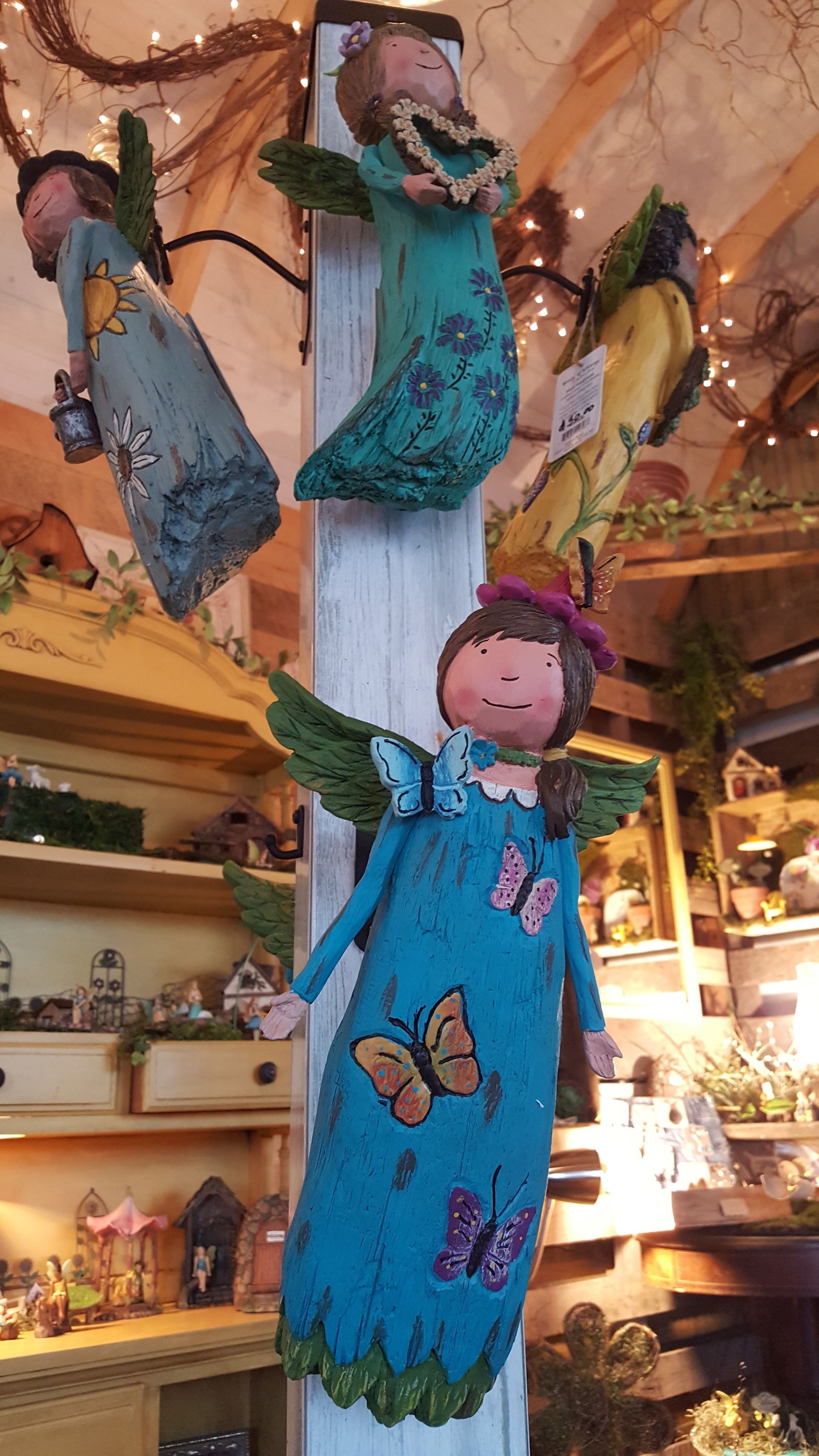 Angels with green wings and dresses, decorated with butterflies, displayed at a shop.