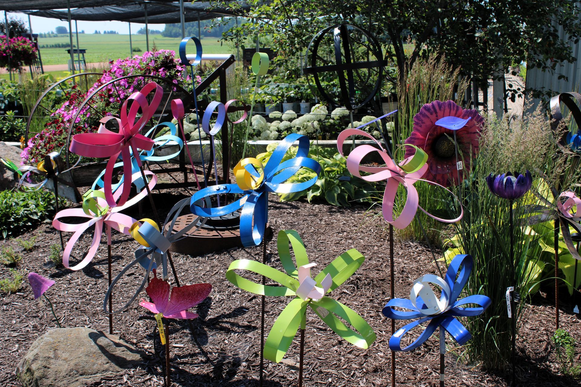 Colorful metal flower sculptures in a garden setting, displayed in a nursery.