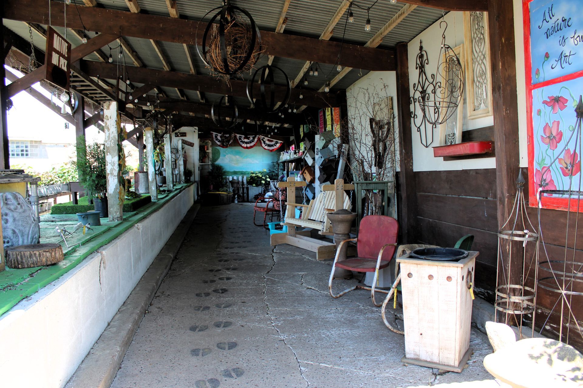 Covered outdoor art space with various sculptures, paintings, and seating.
