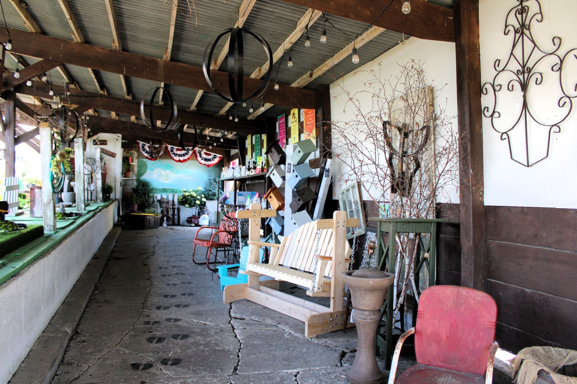 Covered outdoor area with various furniture and decor, including a bench and a red chair.