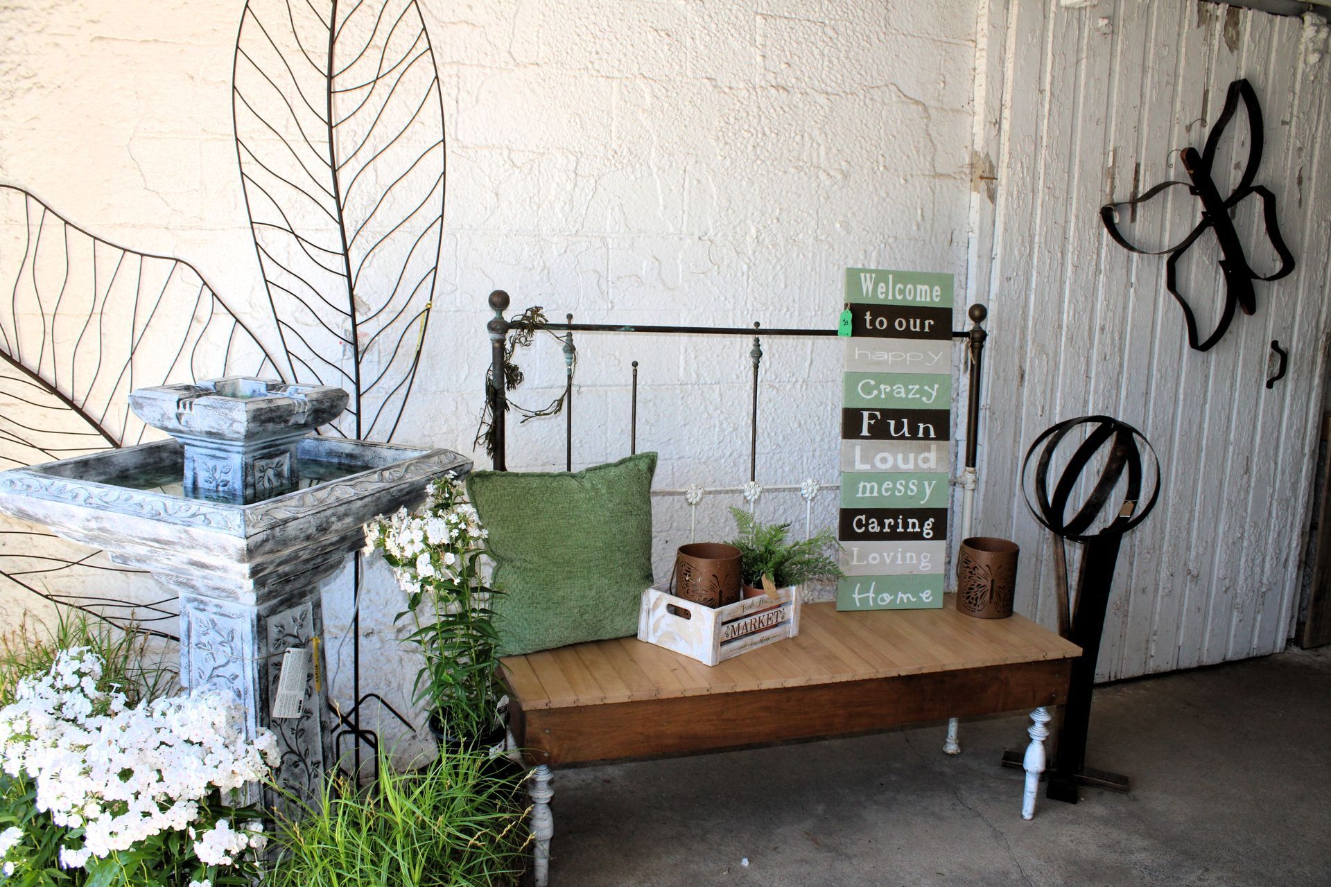 Outdoor seating area with a fountain, a bench with pillows, and decorative signs.