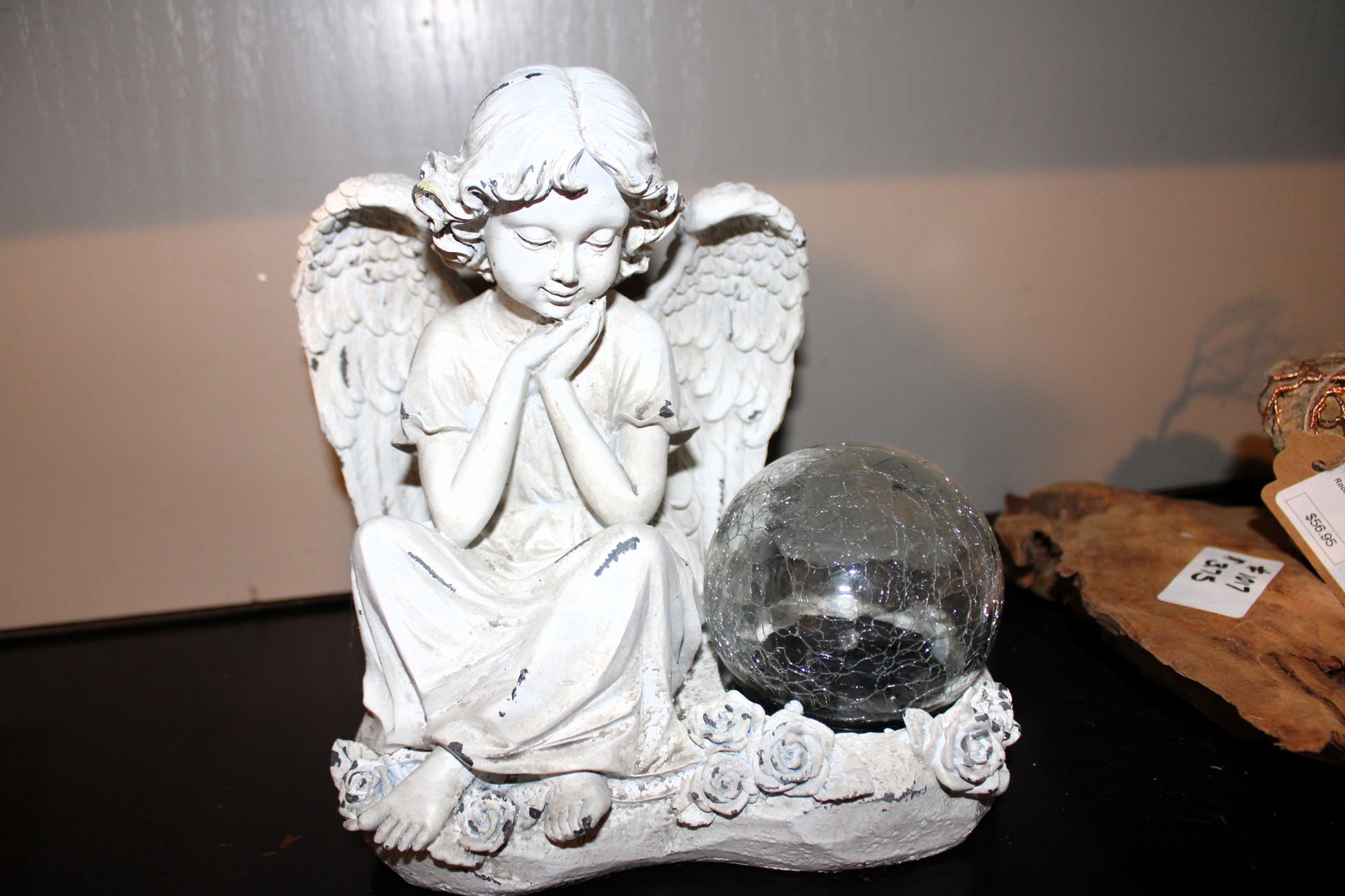 White angel statue with hands clasped, beside a cracked glass ball.