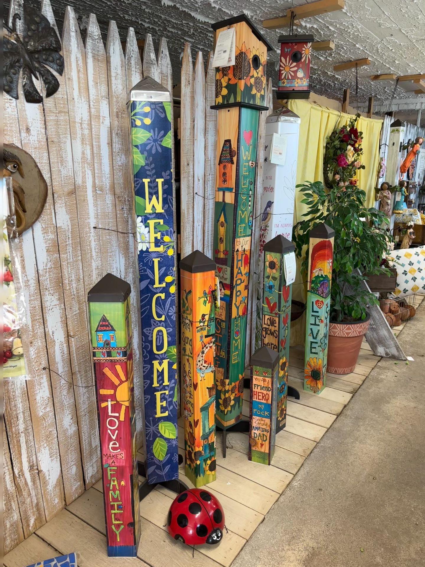 Colorful painted wooden garden stakes with various designs and text, displayed indoors.
