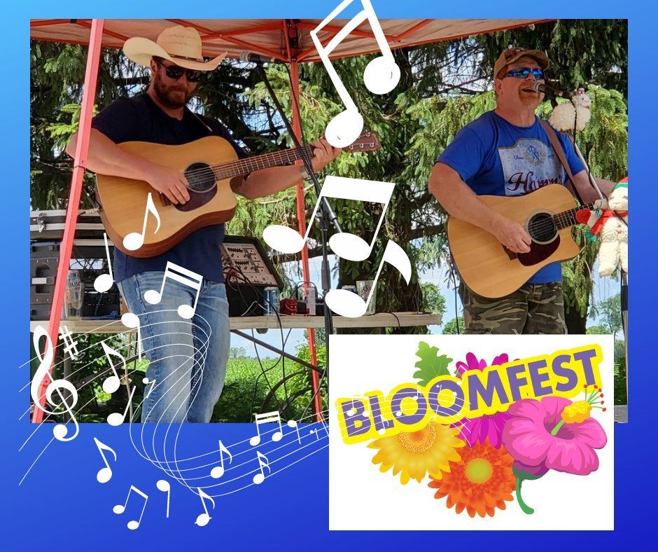 Two men are playing guitars in front of a sign that says bloomfest