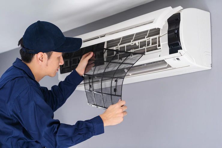 Technician cleaning the filter of a wall-mounted air conditioner unit