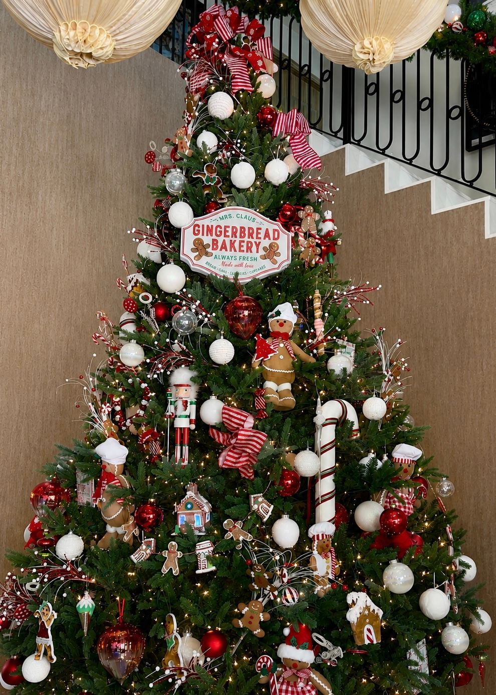 Decorated Christmas tree with red, white, and gold ornaments beside a staircase