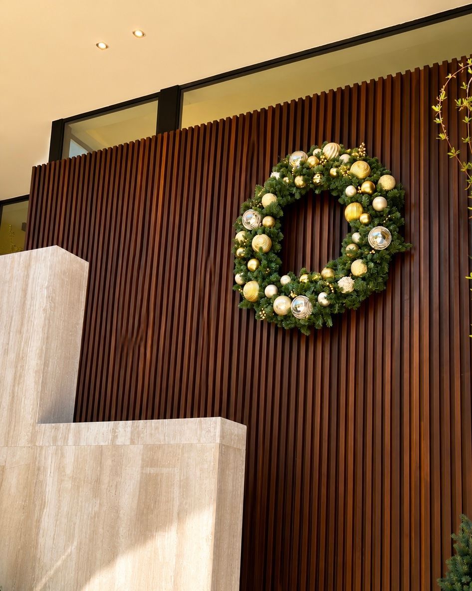 Wood-paneled wall with a green-and-white floral wreath and beige steps in the foreground