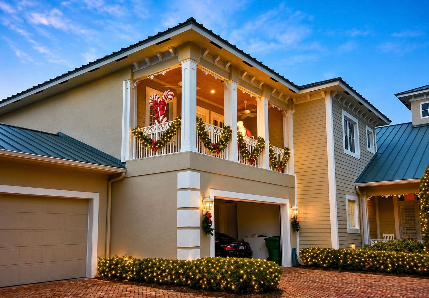 Two-story suburban house with a decorated front balcony, garage, and landscaped bushes at dusk