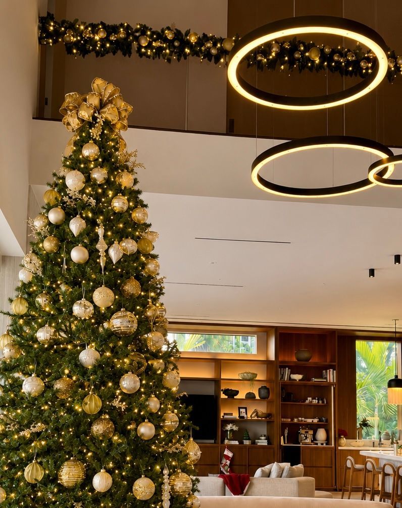 Decorated Christmas tree in a modern lobby with gold ornaments and circular ceiling lights