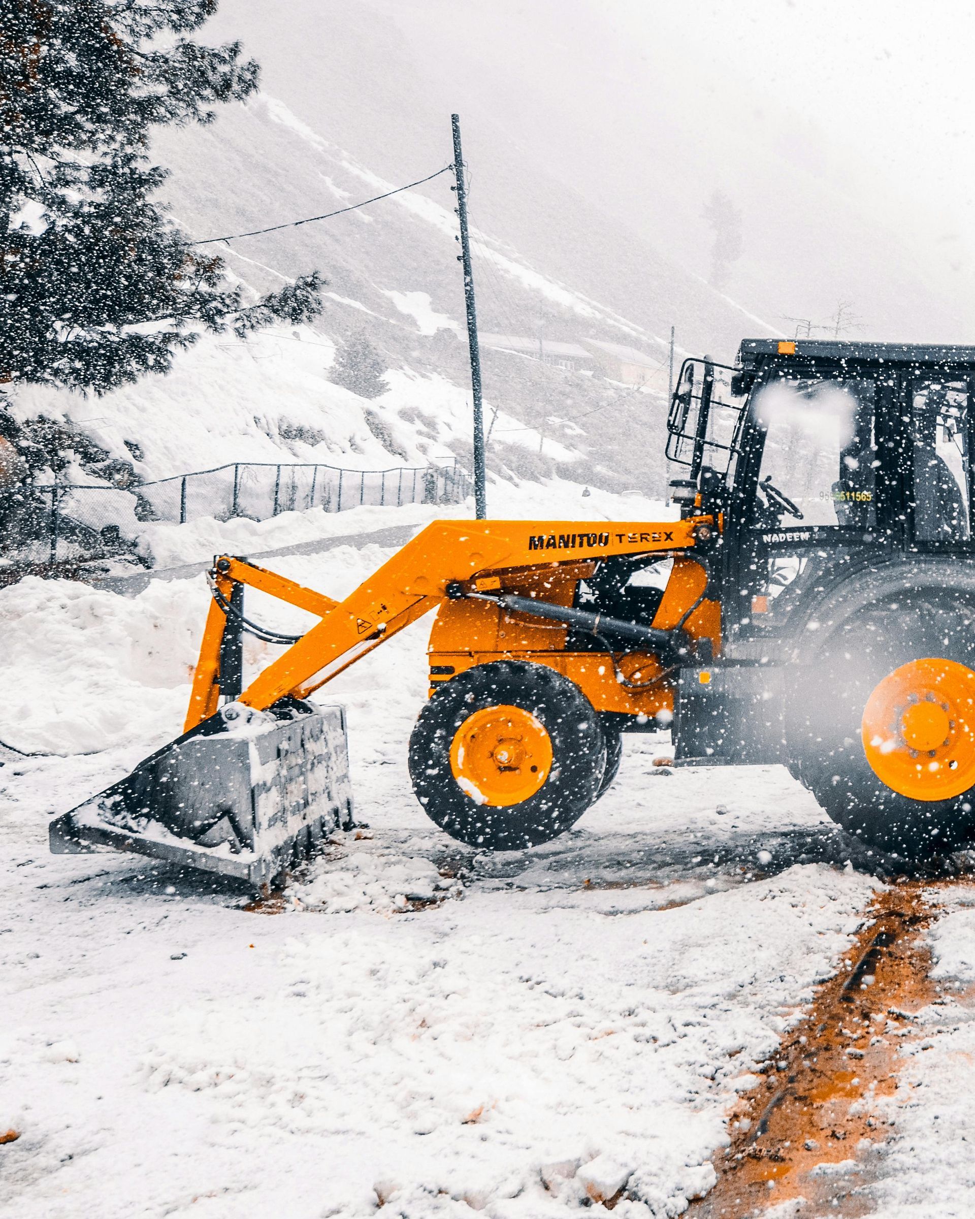 A yellow and black tractor is clearing snow from a road