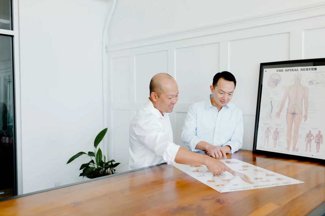 chiropractors Thang Tran, DC and Tan Tran, DC reviewing diagram of the human body.