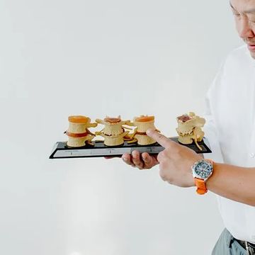 chiropractor  is holding a model of the spine in his hands.