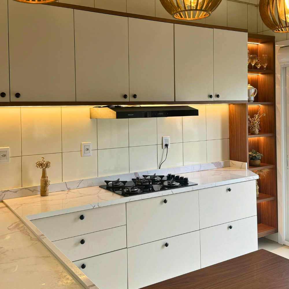 Uma cozinha com uma ilha grande, bancos, geladeira e micro-ondas.