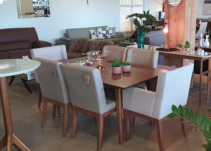 Uma mesa de jantar com cadeiras e um sofá ao fundo.