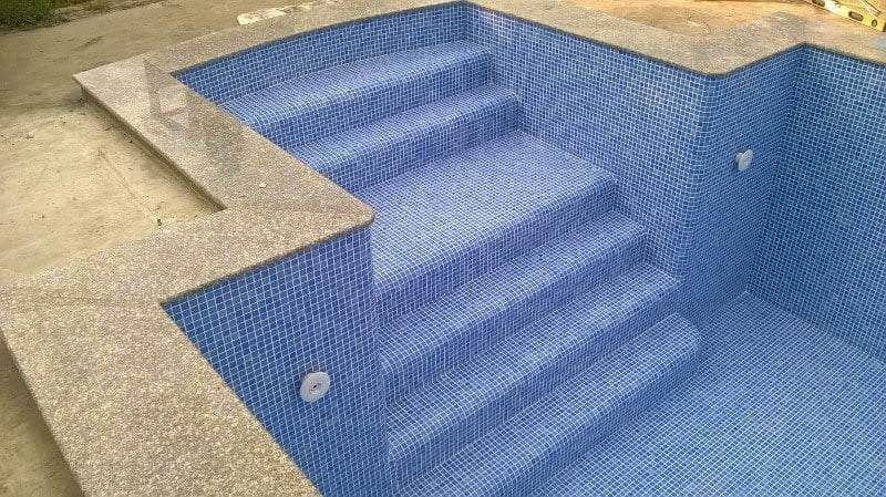 A freshly tiled swimming pool with blue tiles completed by Master Tiling.