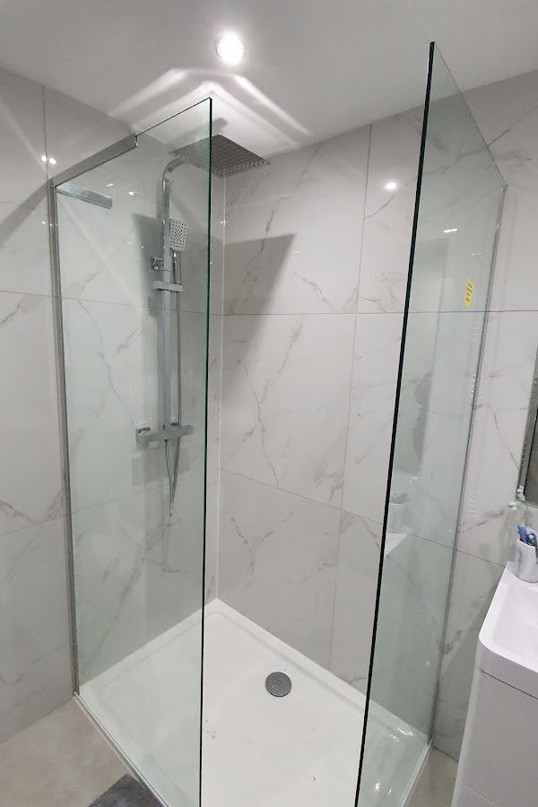 A completed bathroom shower renovation with white marble tiles in London. Expertly crafted by Master Tiling