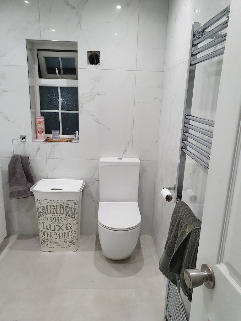 A completed bathroom tiling project in London by Master tiling. The bathroom is expertly finished with soft white and grey marble tiles.