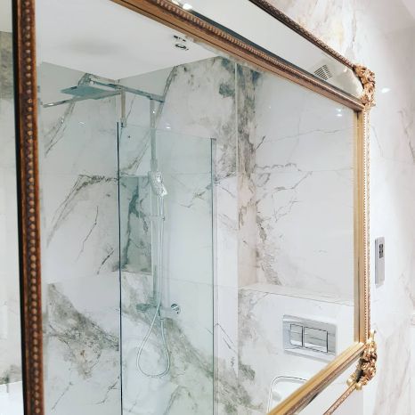 A bathroom with a mirror. Tiled in white marble by Master Tiling in North-West London.