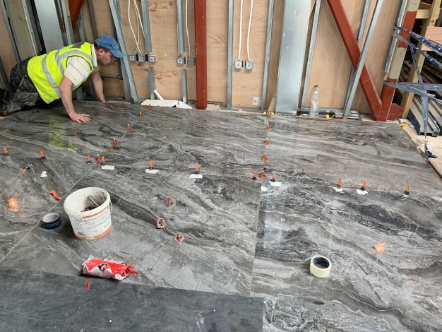 A marble grey shiny tiled floor in Holland apartments London. In the process of being expertly completed by Master Tiling.