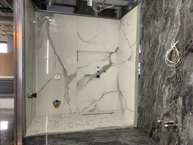 A marble grey and white shiny tiled bathroom in Holland apartments London. Expertly completed by Master Tiling.