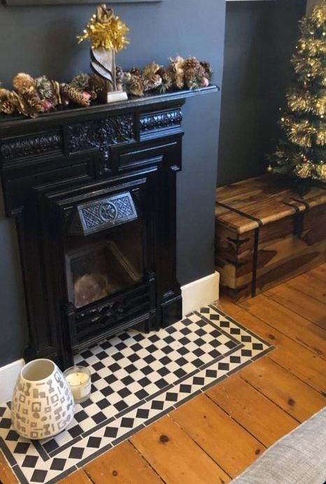 A living room with a fireplace and a Christmas tree. The fireplace is tiled in a checkered pattern.