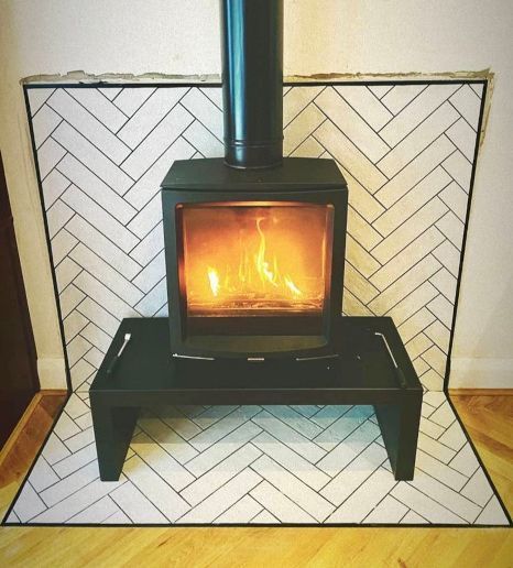 A fireplace with a herringbone pattern tiled surround and a stove in it.