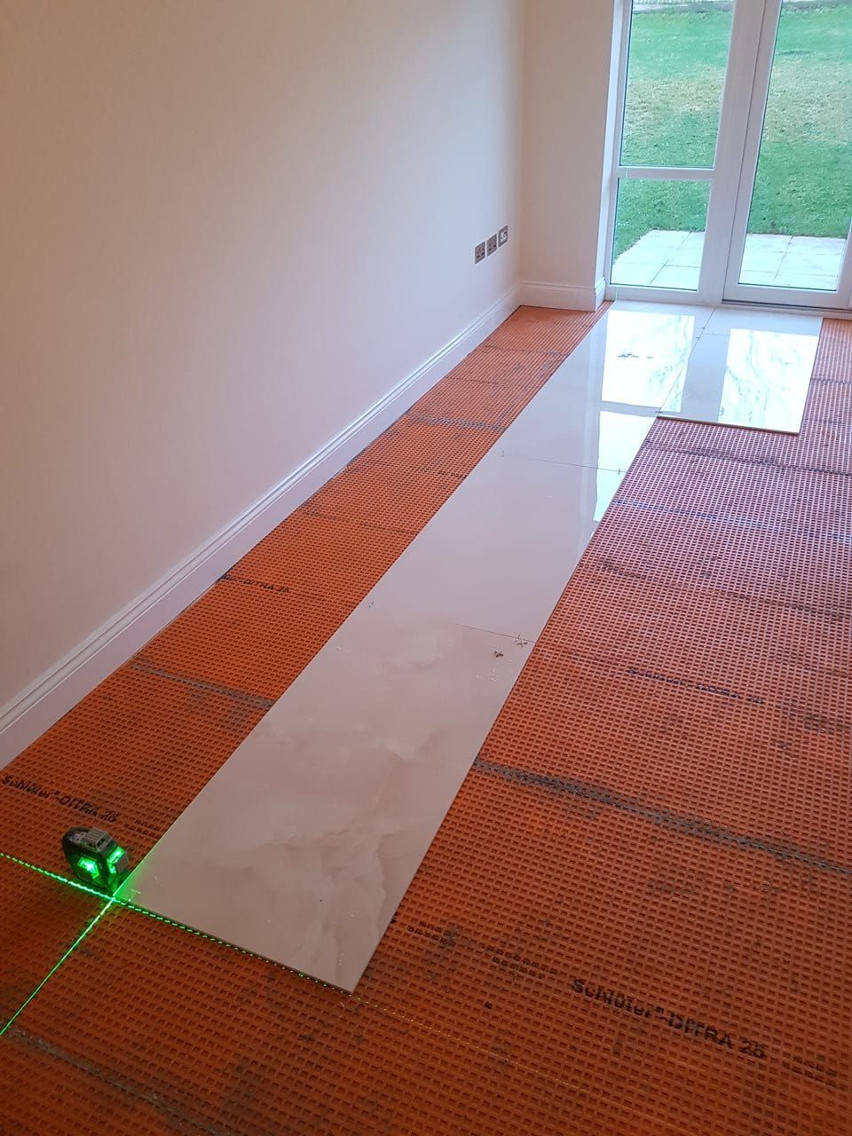 New floor tiles lined up with laser precision on top of floor protective mats in a new floor completion for a lovely London home using white Onyx-effect marble tiles, completed by Master Tiling