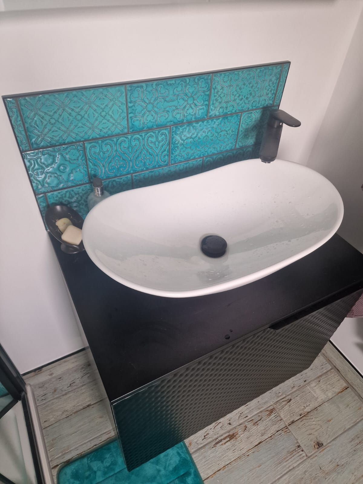 A freshly tiled bathroom sink backsplash in light turquoise blue metro tiles in a London home, completed by Master Tiling