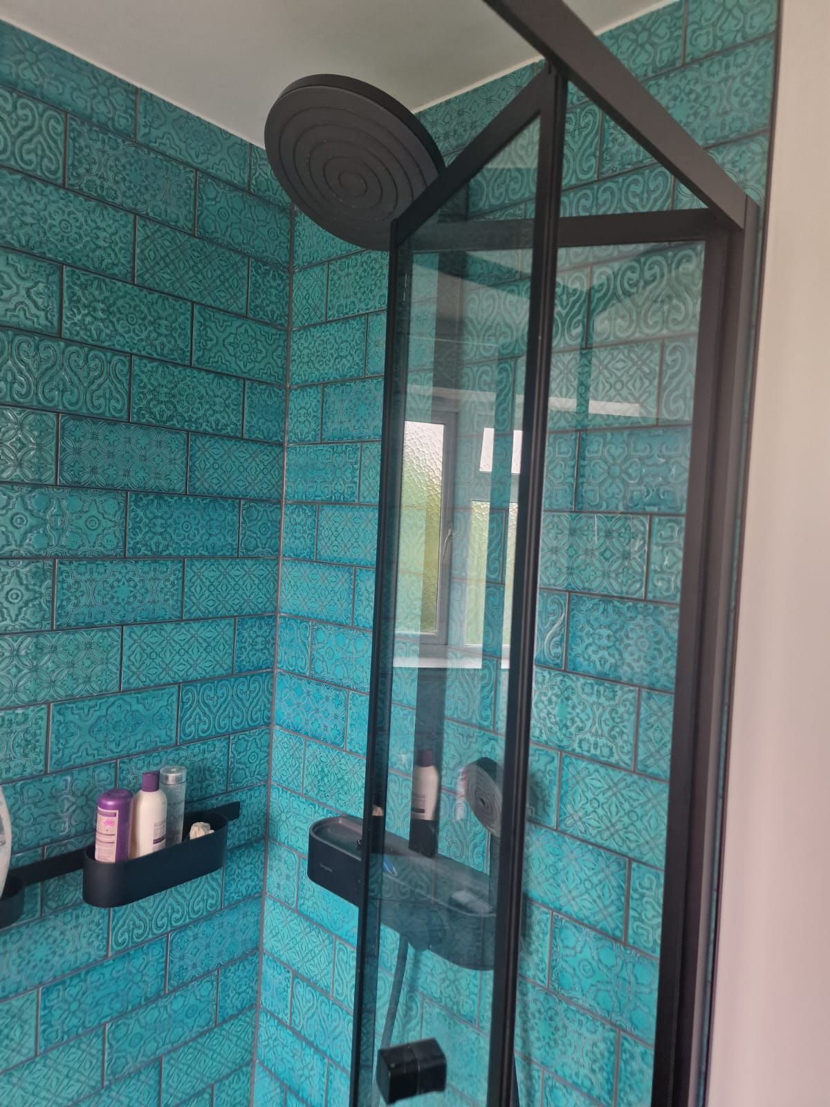 A completed bathroom shower renovation in London. The shower walls are tiled with light blue, patterned metro tiles. Completed by Master Tiling