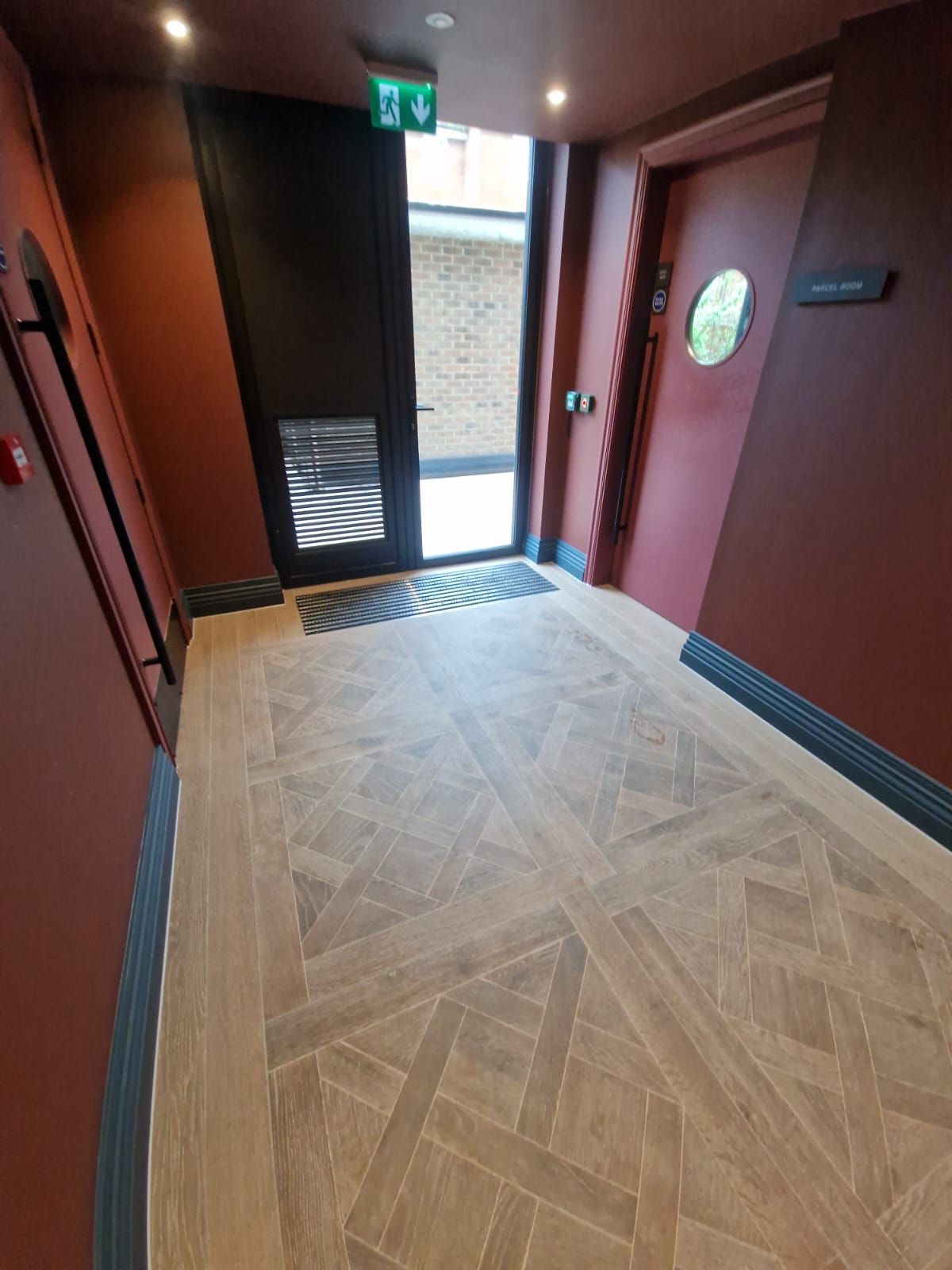 A hallway of the Brondesbury hotel Willesden in London, expertly tiled with brown wood-effect tiles by Master Tiling