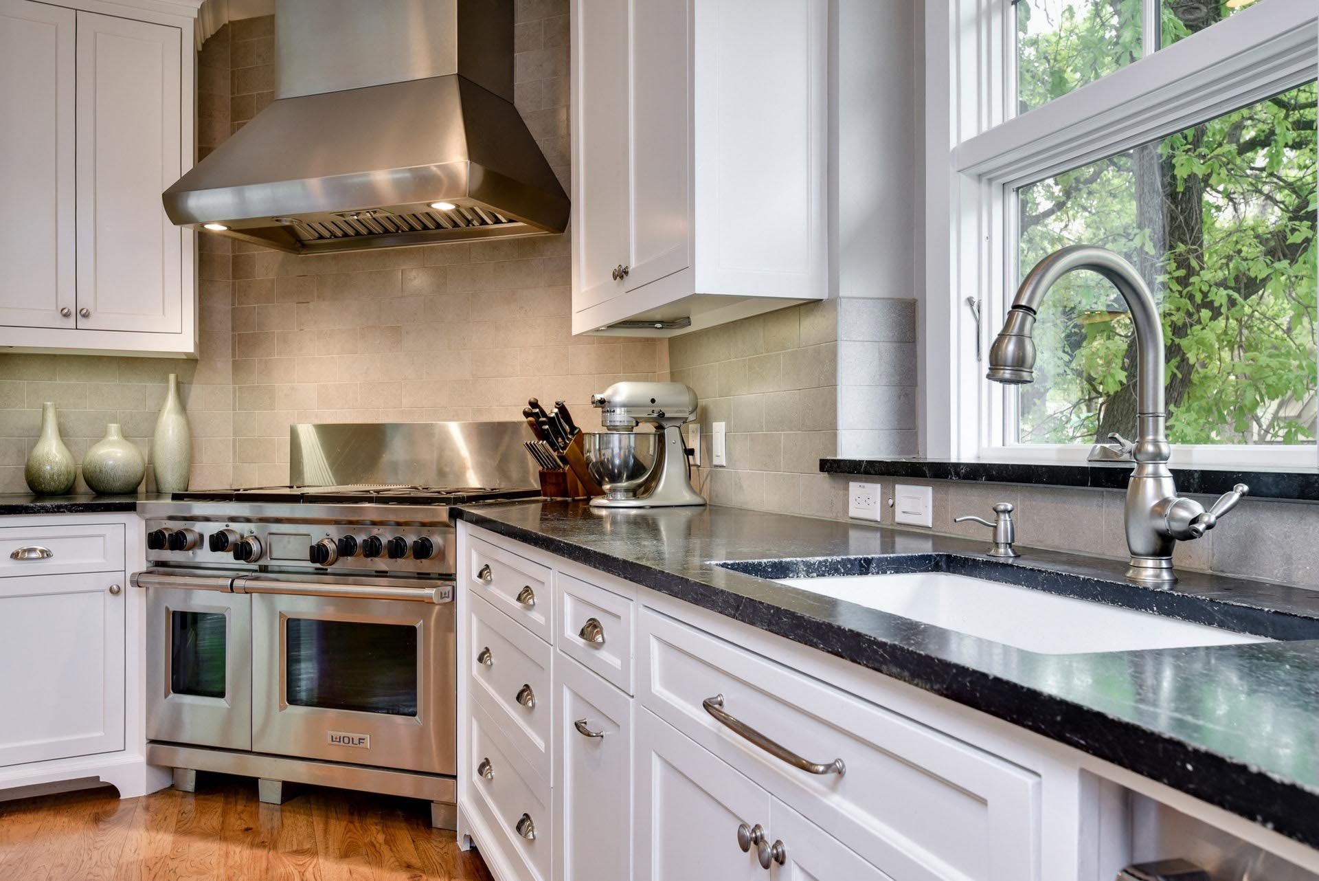 Modern kitchen with white cabinets, stainless steel appliances, and dark countertops.